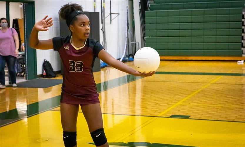 A volleyball player prepares to serve